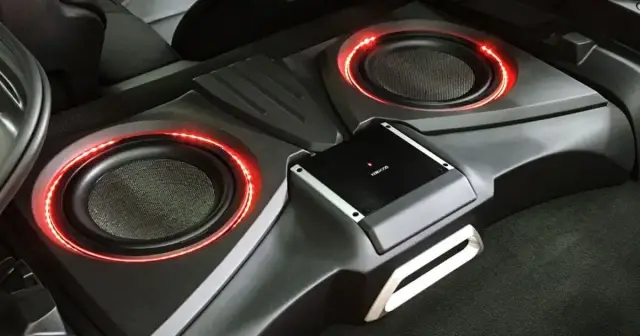 Dual subwoofers with red accent lighting installed in a trunk
